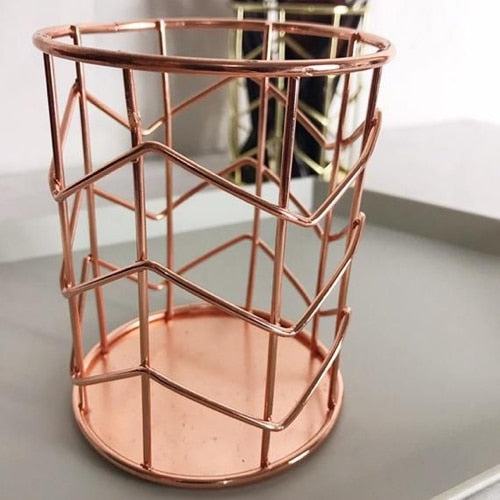 Rose gold metal umbrella stand on a neutral background