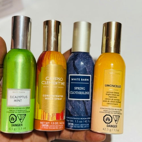 Four concentrated room spray bottles held in a hand against a white background