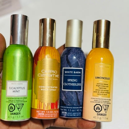 Four concentrated room spray bottles held in a hand against a white background